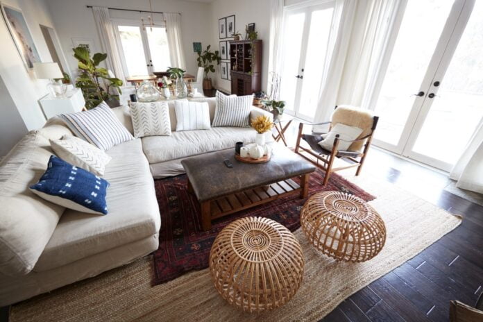 A family living room with French windows and a large comfortable corner sofa, seen in daylight, incidental people in shot