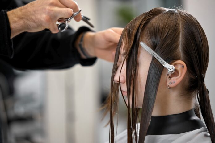 male hairdresser is combing the hair of the female client.